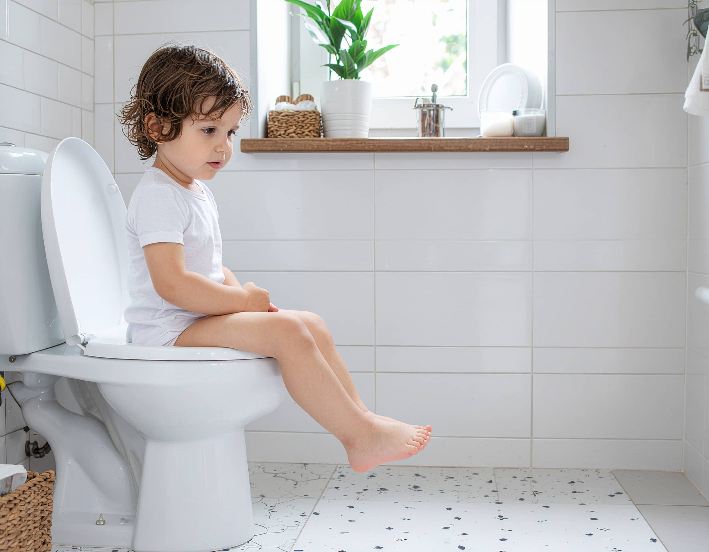Μικρό παιδί κάθεται στη λεκάνη του μπάνιου προσπαθώντας να χρησιμοποιήσει την τουαλέτα μόνο του