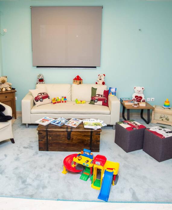 Φιλόξενος παιδικός χώρος υποδοχής με άνετες πολυθρόνες, λούτρινα αρκουδάκια και παιχνίδια, διακοσμημένος σε απαλούς γαλάζιους τόνους